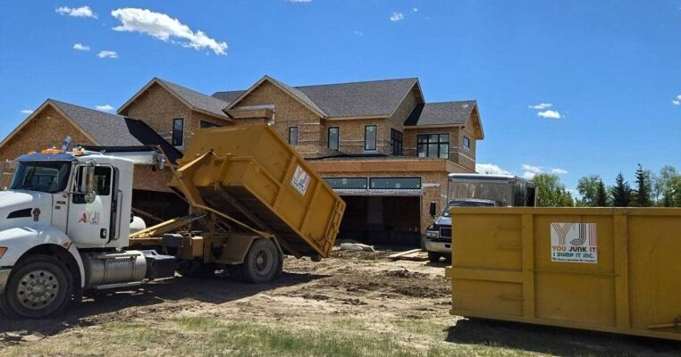 Dump truck collecting debris at a residential construction site for junk removal.
