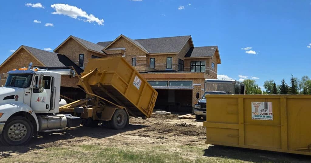 Dump truck collecting debris at a residential construction site for junk removal.