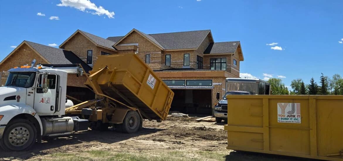Dump truck collecting debris at a residential construction site for junk removal.