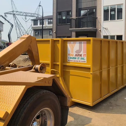 YJI truck dropping off a clean new dumpster at a construction site