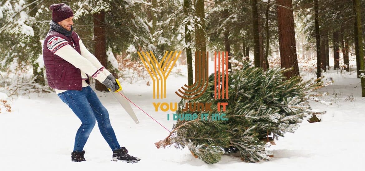 a person holding a saw and carrying a christmas tree