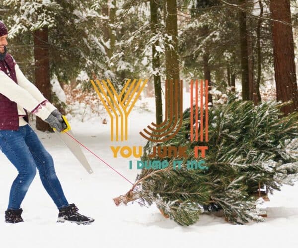 a person holding a saw and carrying a christmas tree